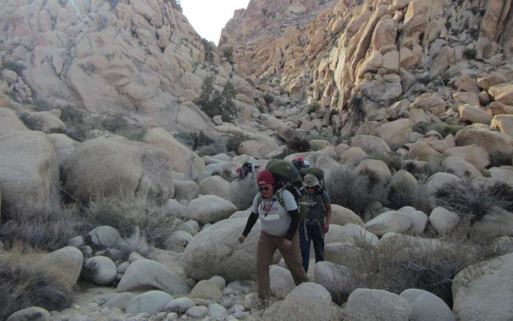 a group of people navigate over large rocks in Joshua Tree National Park